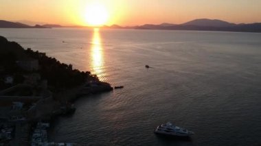 Hava aracı, gün batımında pitoresk liman ve Hydra (veya Ydra) adasının ana köyünün panoramik fotoğrafını çeker. Hydra, Yunanistan 'ın Saronik Körfezi' nde bulunan neoklasik evleri ile önde gelen turizm merkezlerinden biri..