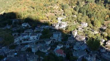 Aerial panoramic view over the picturesque village Papigo in Epirus, Greece at sunset. Scenic aerial view of traditional Greek villages in Autumn. Epirus, Greece, Europe.