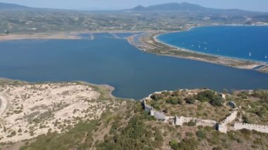 Aerial panorama view over the famous castle of Navarino located on the top of semicircular sandy beach and lagoon, Voidokilia in Messenia, Greece