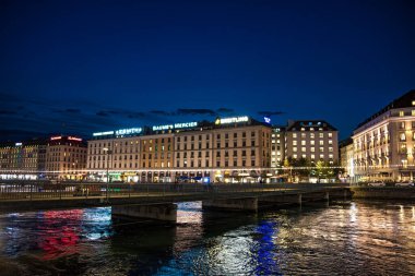 Cenevre, İsviçre - 30 Ağustos 2023: Rhone Nehri ve Cenevre şehrindeki cephelerin manzarası İsviçre 'nin Cenevre kentinde gece aydınlandı