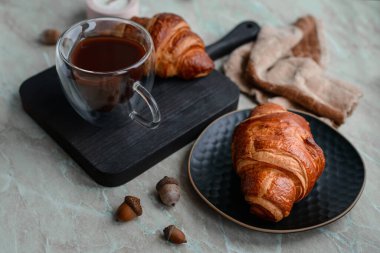 Çikolatalı çıtır kruvasan ve açık beton arka planda canlandırıcı bir fincan kahve. Lezzetli besleyici kahvaltı.