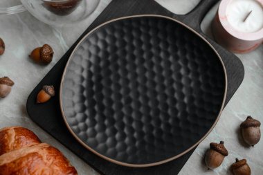 Gri beton arka planda ahşap kesme tahtasındaki güzel siyah tabak