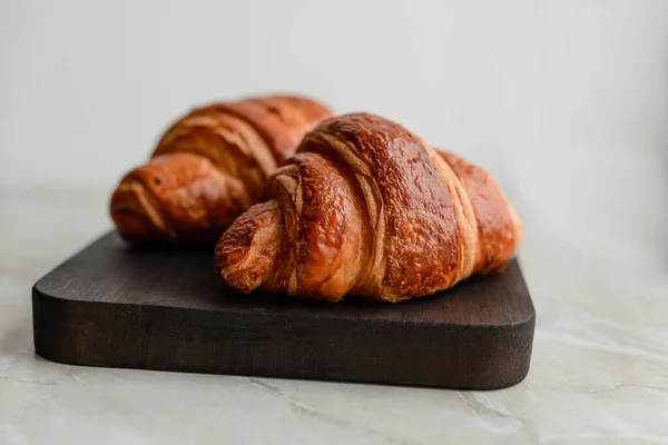 stock image Delicious crispy croissant with chocolate with a cup of invigorating coffee on a light concrete background. Delicious nutritious breakfast