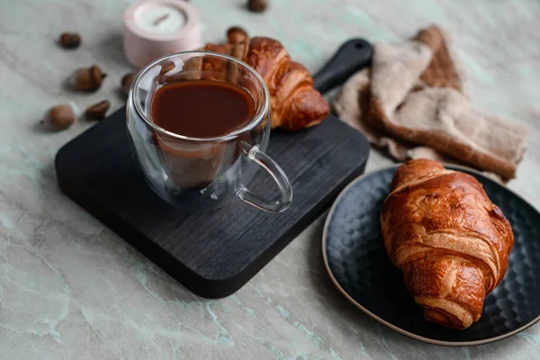 stock image Delicious crispy croissant with chocolate with a cup of invigorating coffee on a light concrete background. Delicious nutritious breakfast