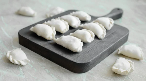 stock image Beautiful raw stuffed dumplings on a wooden cutting board. Delicious fast food