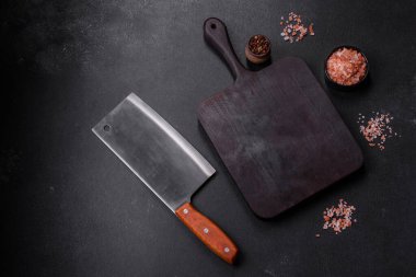 Ahşap kesme tahtası, mutfak aletleri ve siyah beton arka plan. Evde yemek pişirmek.