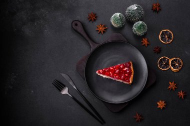 Ev yapımı lezzetli peynirli kek, jöle ve ahududu arkaplanda siyah bir tabakta.