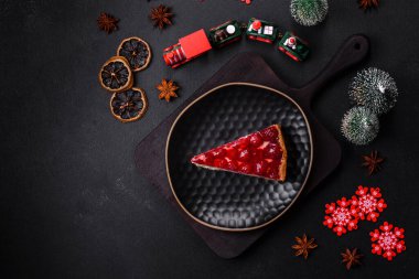 Ev yapımı lezzetli peynirli kek, jöle ve ahududu arkaplanda siyah bir tabakta.