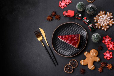 Ev yapımı lezzetli peynirli kek, jöle ve ahududu arkaplanda siyah bir tabakta.