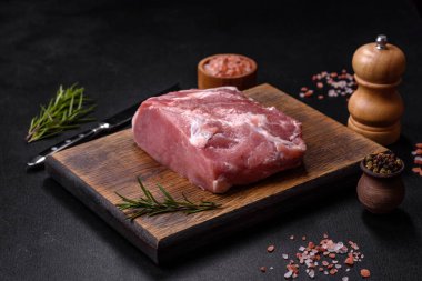 Taze çiğ domuz eti, baharatlar, tuz ve otlar ahşap bir kesme tahtasının üzerinde. Evde ızgara yemek pişirmek.