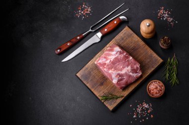 Taze çiğ domuz eti, baharatlar, tuz ve otlar ahşap bir kesme tahtasının üzerinde. Evde ızgara yemek pişirmek.
