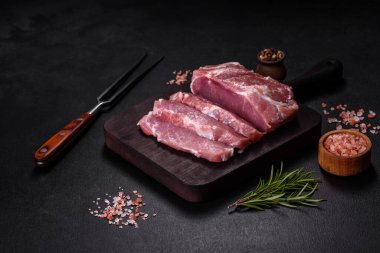 Taze çiğ domuz eti, baharatlar, tuz ve otlar ahşap bir kesme tahtasının üzerinde. Evde ızgara yemek pişirmek.