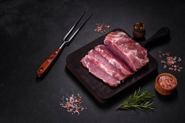 Taze çiğ domuz eti, baharatlar, tuz ve otlar ahşap bir kesme tahtasının üzerinde. Evde ızgara yemek pişirmek.