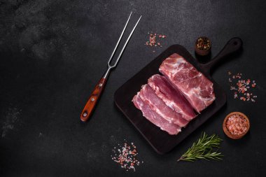 Taze çiğ domuz eti, baharatlar, tuz ve otlar ahşap bir kesme tahtasının üzerinde. Evde ızgara yemek pişirmek.