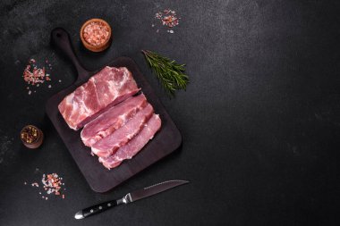 Taze çiğ domuz eti, baharatlar, tuz ve otlar ahşap bir kesme tahtasının üzerinde. Evde ızgara yemek pişirmek.