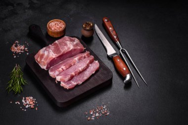 Taze çiğ domuz eti, baharatlar, tuz ve otlar ahşap bir kesme tahtasının üzerinde. Evde ızgara yemek pişirmek.