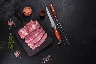 Taze çiğ domuz eti, baharatlar, tuz ve otlar ahşap bir kesme tahtasının üzerinde. Evde ızgara yemek pişirmek.