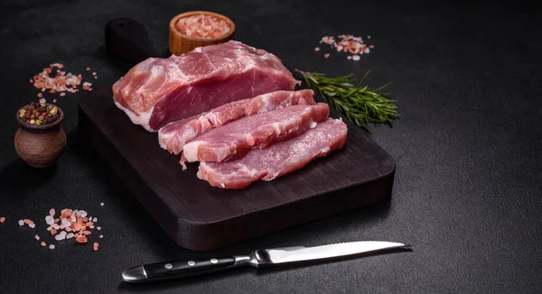 stock image Fresh piece of raw pork with spices, salt and herbs on a wooden cutting board. Cooking grilled meals at home