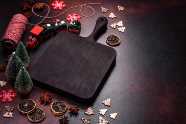 Kahverengi beton bir masada farklı Noel süslemeleri ve zencefilli çörekler. Yeni yıl kutlamaları için hazırlık