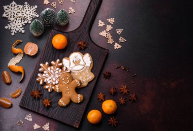 Bayram oyuncakları, mandalinalar ve koyu beton arka planda zencefilli çöreklerle güzel Noel süslemeleri. Noel masasını hazırlıyorum.