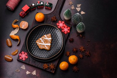 Bayram oyuncakları, mandalinalar ve koyu beton arka planda zencefilli çöreklerle güzel Noel süslemeleri. Noel masasını hazırlıyorum.