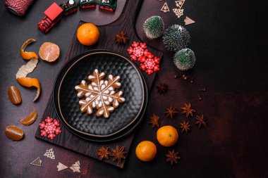 Bayram oyuncakları, mandalinalar ve koyu beton arka planda zencefilli çöreklerle güzel Noel süslemeleri. Noel masasını hazırlıyorum.