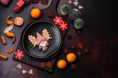 Bayram oyuncakları, mandalinalar ve koyu beton arka planda zencefilli çöreklerle güzel Noel süslemeleri. Noel masasını hazırlıyorum.