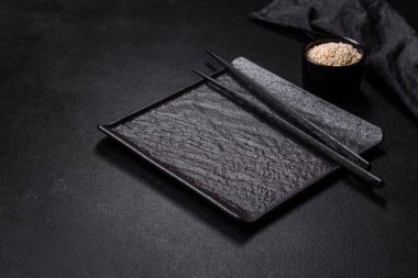 Koyu beton arka planda Asya yemekleri için tahta çubuklu boş tabak. Asya mutfağının hazırlanması