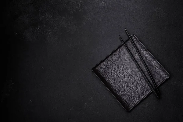 stock image Empty plate with wooden sticks for Asian food on a dark concrete background. Preparation of Asian cuisine