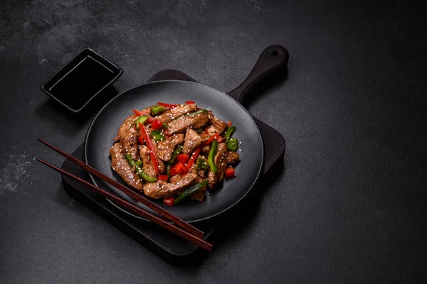 テーブルの上の皿に赤ピーマンとゴマを盛ったおいしいアジアの照り焼き肉 — ストック写真