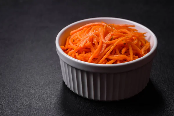 Tasty spicy Korean carrot with spices and herbs on a dark concrete background. Asian food