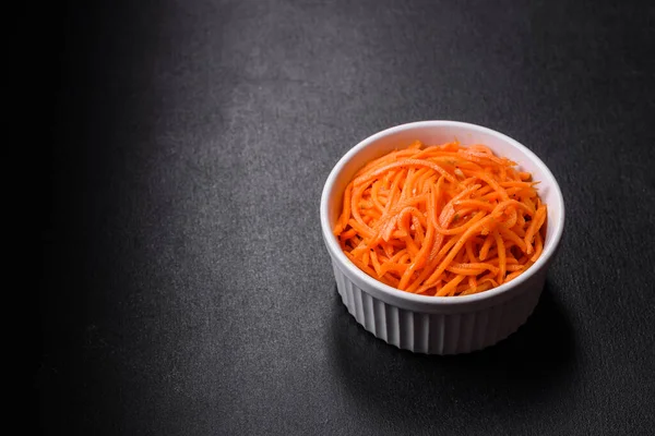 Tasty spicy Korean carrot with spices and herbs on a dark concrete background. Asian food
