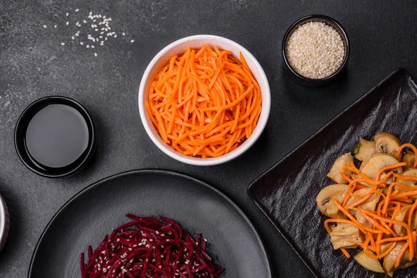 Tasty spicy Korean carrot with spices and herbs on a dark concrete background. Asian food