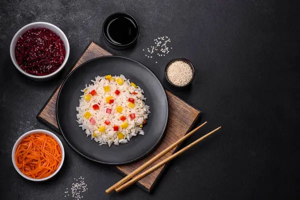 stock image Tasty Asian dish of rice, pepper, spices and herbs in a black plate on a dark concrete background