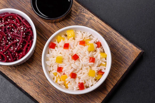 stock image Tasty Asian dish of rice, pepper, spices and herbs in a black plate on a dark concrete background