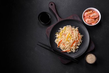 Delicious fresh rice noodles with shrimp, spices and herbs on a dark concrete background clipart