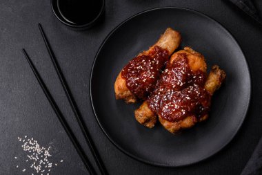 Teriyaki soslu baharatlı tavuk budu ve koyu beton arka planda susam tohumu.