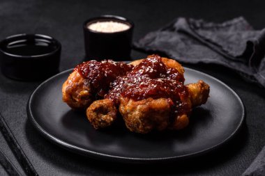 Teriyaki soslu baharatlı tavuk budu ve koyu beton arka planda susam tohumu.