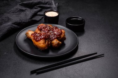 Teriyaki soslu baharatlı tavuk budu ve koyu beton arka planda susam tohumu.