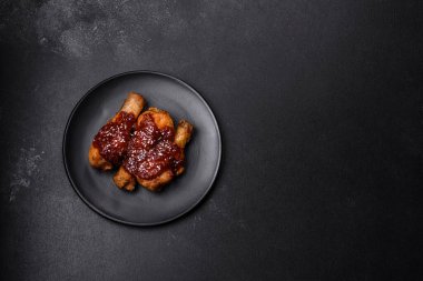 Teriyaki soslu baharatlı tavuk budu ve koyu beton arka planda susam tohumu.