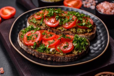 Domatesli lezzetli bruschetta, mozzarella, fesleğen, baharat ve otlar koyu beton arka planda.