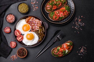 Lezzetli kahvaltı yumurta, domuz pastırması, fasulye, domates, esmer çimento arka planda baharatlar ve otlardan oluşur.