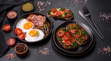 Lezzetli kahvaltı yumurta, domuz pastırması, fasulye, domates, esmer çimento arka planda baharatlar ve otlardan oluşur.