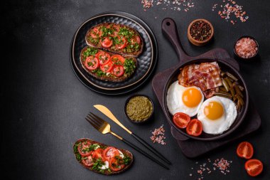 Lezzetli kahvaltı yumurta, domuz pastırması, fasulye, domates, esmer çimento arka planda baharatlar ve otlardan oluşur.