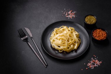 Pesto soslu lezzetli taze makarna ve siyah bir tabakta koyu beton arka planda deniz ürünleri.