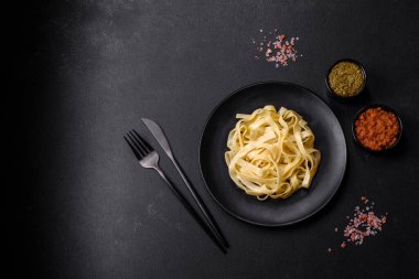 Pesto soslu lezzetli taze makarna ve siyah bir tabakta koyu beton arka planda deniz ürünleri.