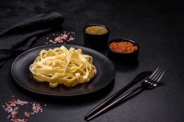 Pesto soslu lezzetli taze makarna ve siyah bir tabakta koyu beton arka planda deniz ürünleri.