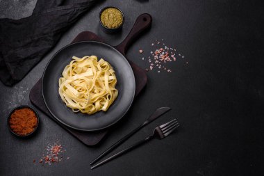 Pesto soslu lezzetli taze makarna ve siyah bir tabakta koyu beton arka planda deniz ürünleri.
