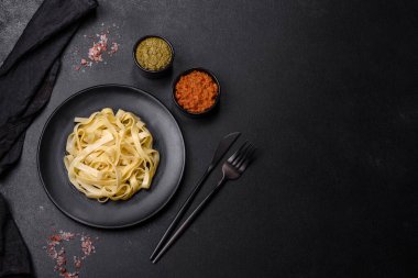 Pesto soslu lezzetli taze makarna ve siyah bir tabakta koyu beton arka planda deniz ürünleri.