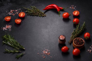 Kaburgalarda taze çiğ domuz eti, baharatlar ve ahşap kesme tahtasındaki otlar koyu beton arka planda.